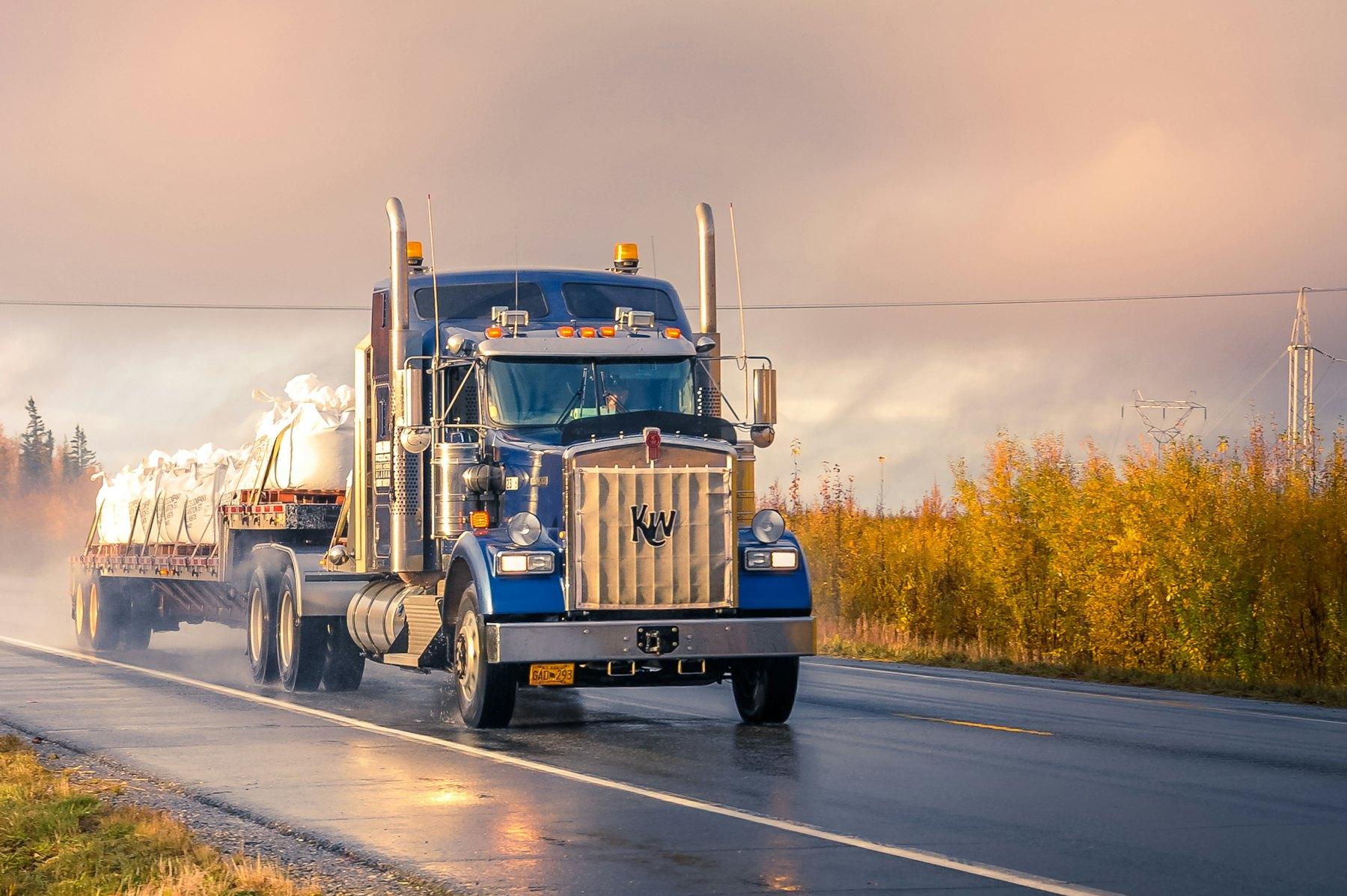 Flatbed tractor-trailer on a wet highway