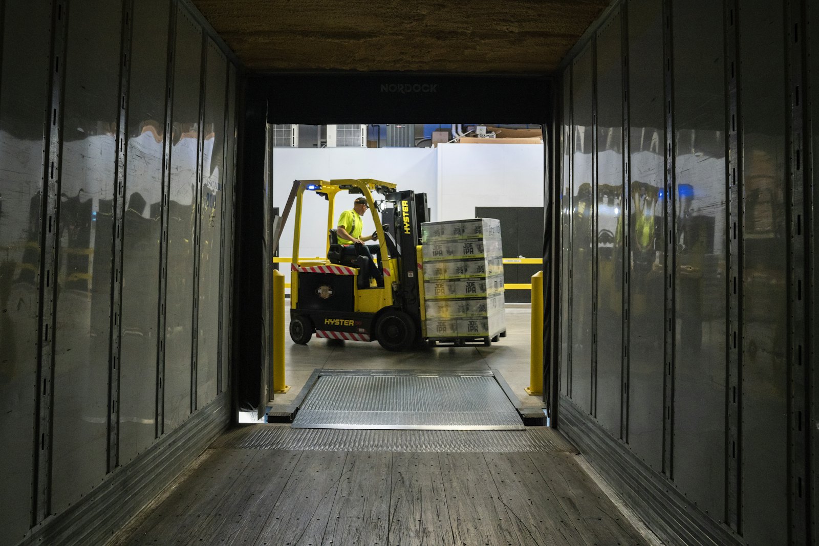 View from inside an empty trailer as a forklift brings a pallet up the dock plate